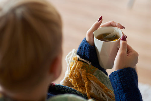 Woman's hand holding a mug of tea with lemon