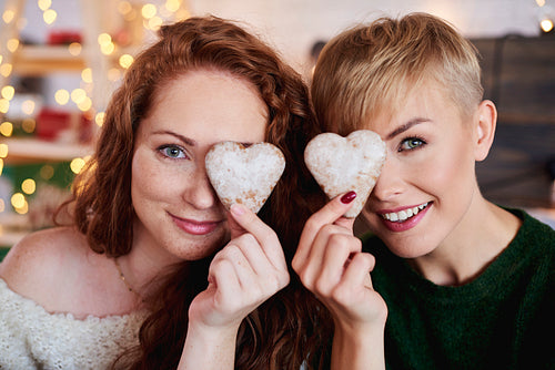 Smiling girls holding heart shaped gingerbread cookies