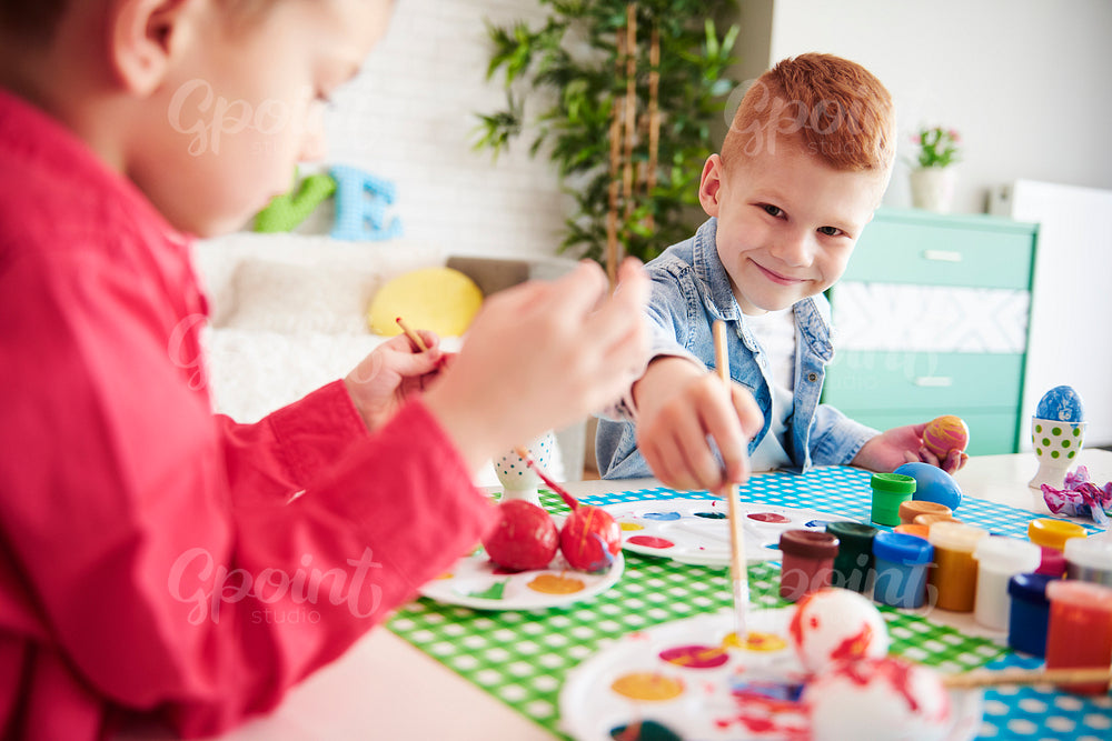 Smiling boy painting easter eggs