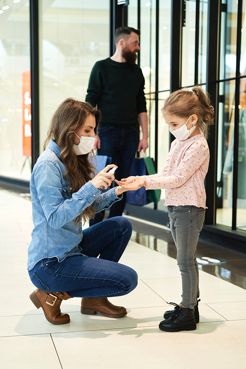 Mom disinfects her daughter's hands while shopping at the mall