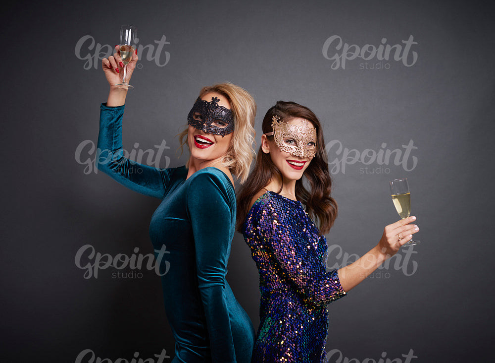 Portrait of women with masks and champagne at the party