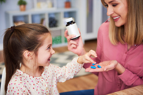 Young mum giving her little daughter the medicine
