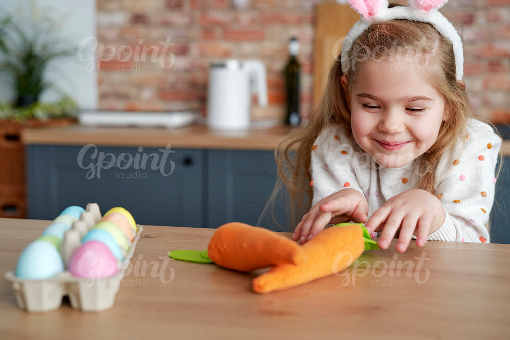 Playful girl steals a handmade carrot from the table