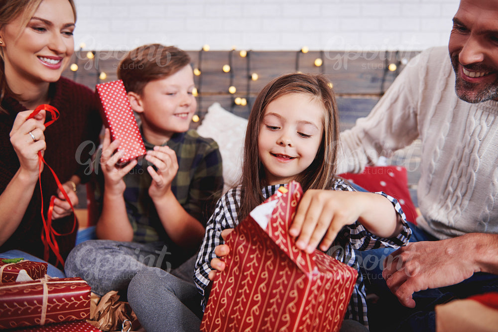 Children opening christmas present with parents