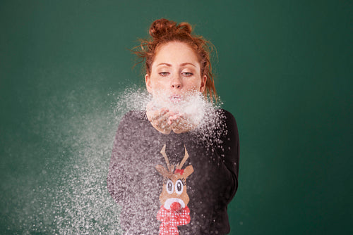 Young woman blowing fake snow