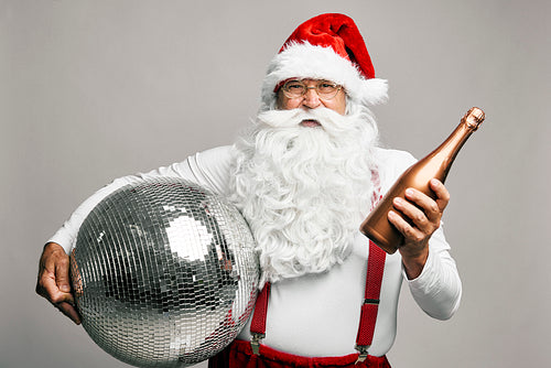 Caucasian Santa Claus celebrating with bottle of champagne and disco ball