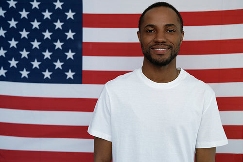 Portrait of cheerful black man on American flag background