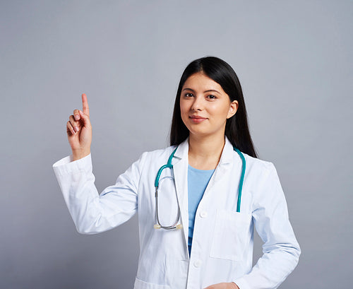 Female Asian doctor pointing somewhere up