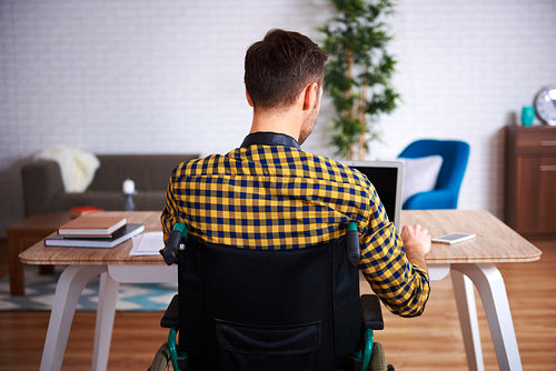 Rear view of disabled man using laptop