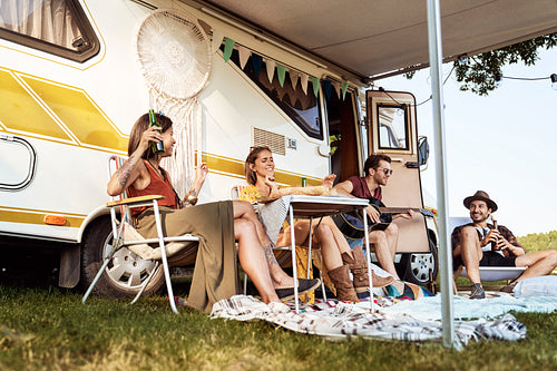 Group of young friends spending time on the camper side with music of guitar