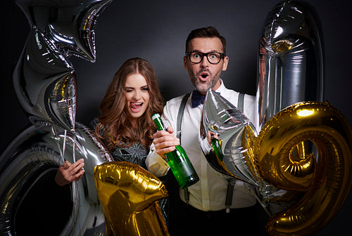 Cheerful couple with champagne and ballons celebrating