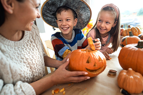Mom with kids preparing pumpkins for Halloween