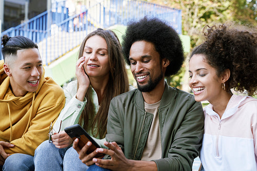Group of friends sitting together with mobile phone