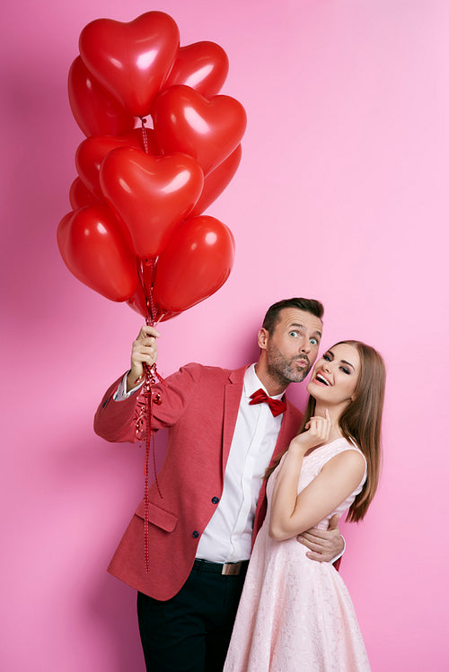 Affectionate couple with heart shape balloons flirting
