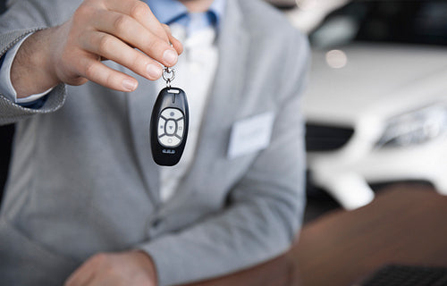 Low section of car salesman with car key