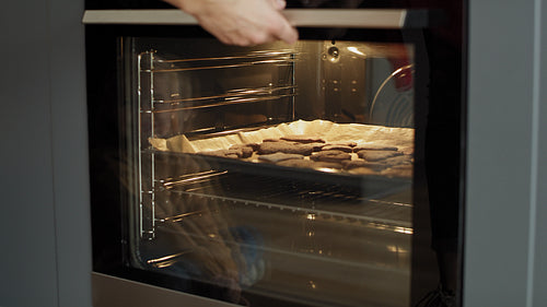 Video of woman taking out homemade gingerbread cookies from the oven
