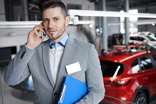 Car salesman on phone in the showroom