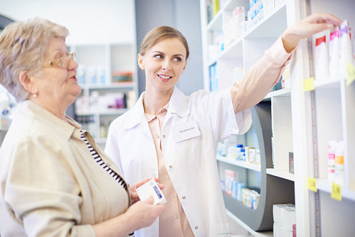 Pharmacist with client examining medicinal products