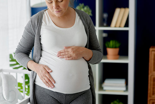 Horizontal image of pregnant woman stroking her abdomen