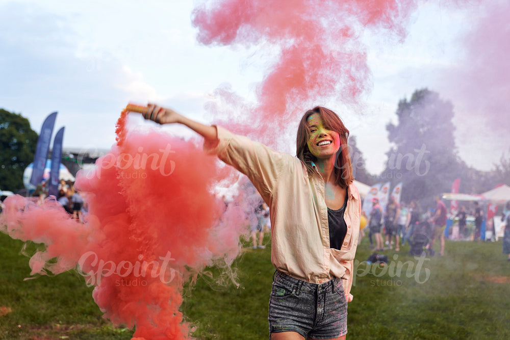 Caucasian woman dancing with coloured smoke bombs at Holi Festival