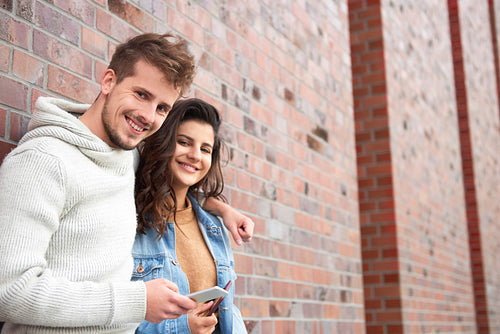 Young couple embracing and holding smart phone