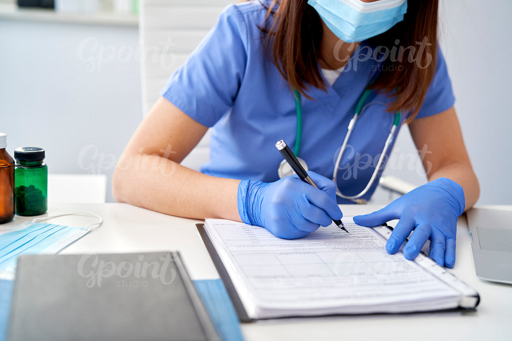 Close up of female doctor filling out medical records