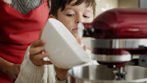 Video of little boy pouring flour into electric mixer bowl