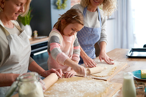 Little girl preparing dough with grandma and mother
