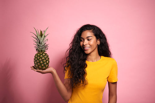 Beautiful African woman holding a pineapple in a studio shot.