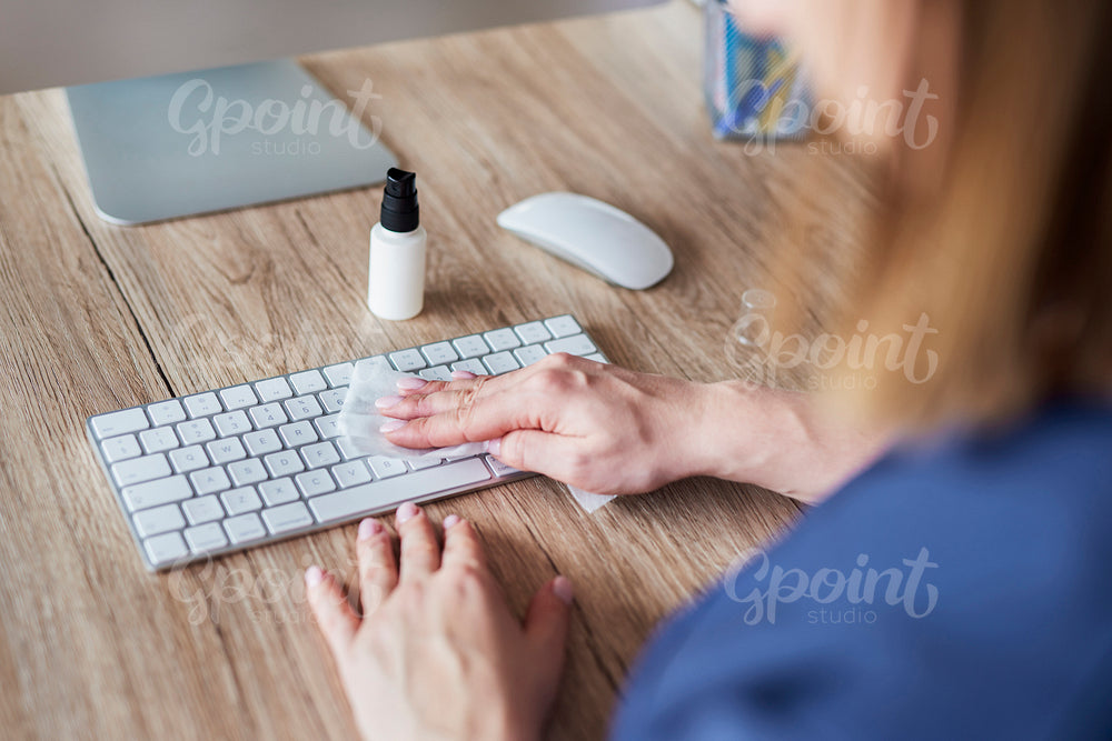 High angle view of woman cleaning keyboard in the office