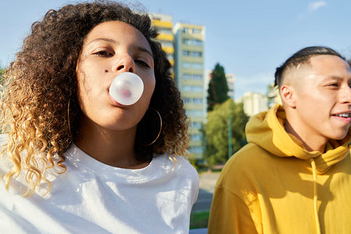 Young couple outdoors and woman making bubble gum balloon