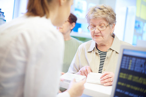 Senior customer at cash register with pharmacist