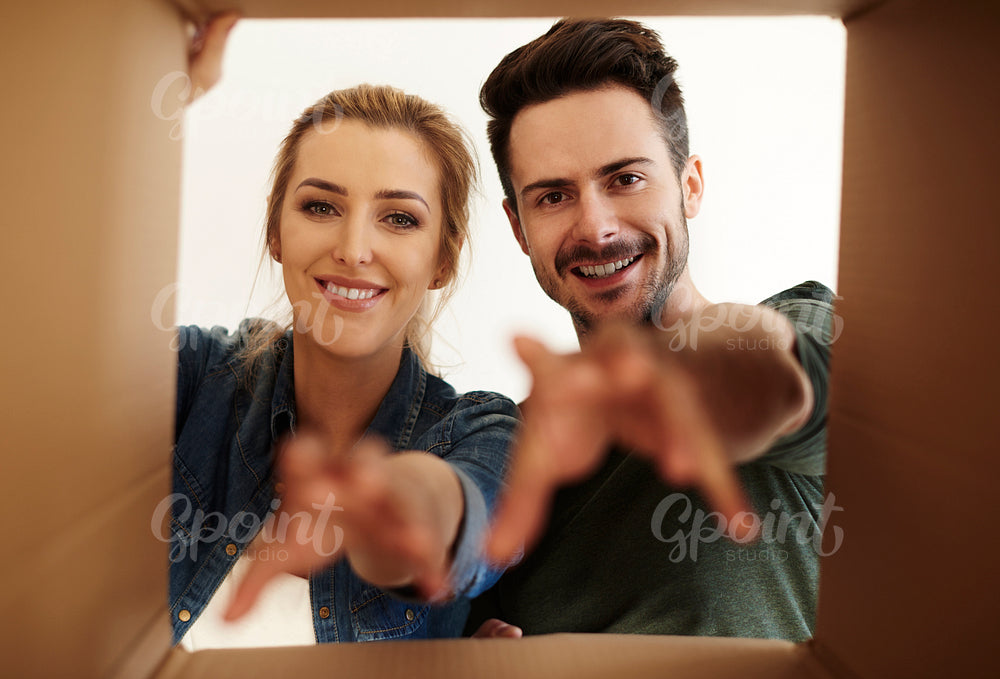 Young couple with reaching hands and carton