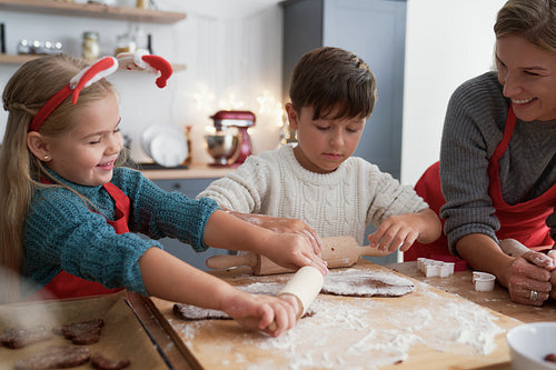 Siblings rolling a gingerbread pastry