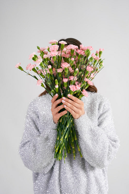 Woman holding bunch of flowers in front of her face