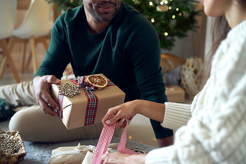 Happy couple packing Christmas present together at home