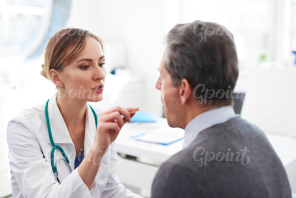 Doctor checking throat of senior man