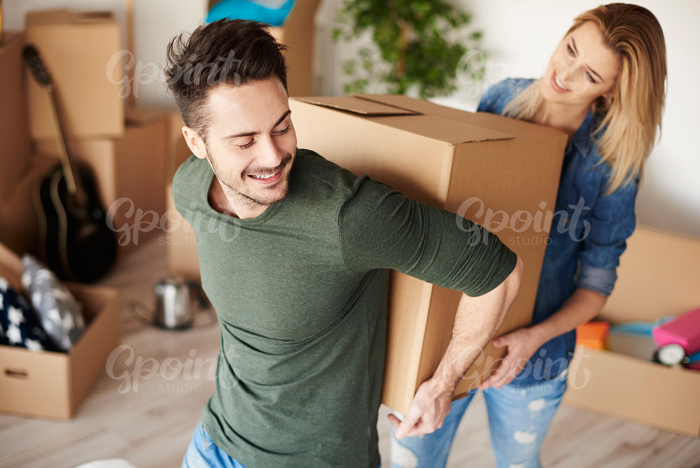 Couple carrying heavy moving boxes together