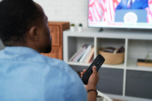 Rear view of black man watching TV