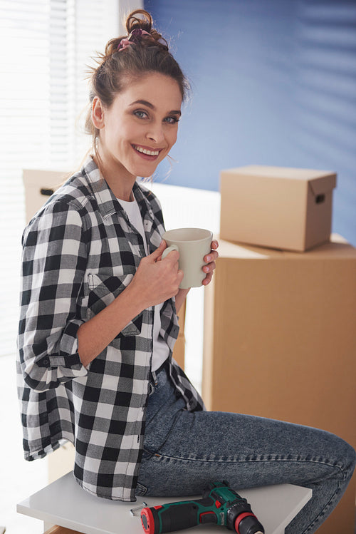 Vertical image of woman having coffee break while moving house