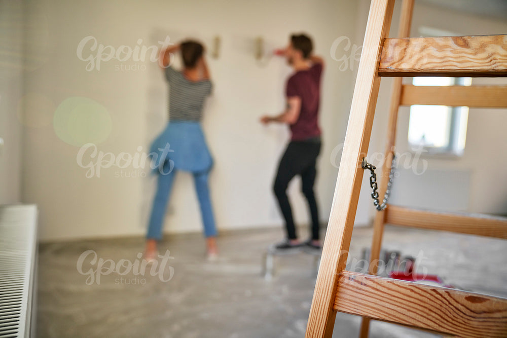Blurred couple in the background painting wall in the house