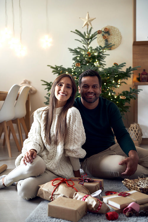 Portrait of happy multi ethnicity couple with Christmas gift at home
