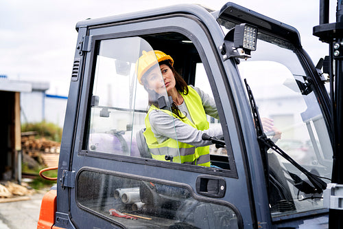 Adult caucasian woman driving a forklift