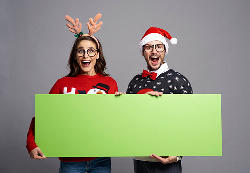 Nerd couple holding greenscreen Christmas banner with copy space