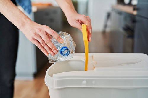 Woman throwing away plastic bottles into the bin