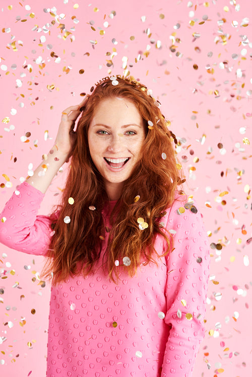 Portrait of cheerful woman among confetti at studio shot