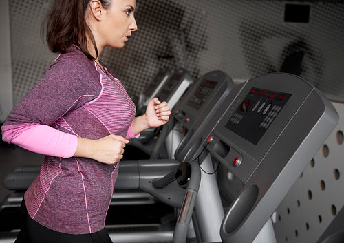 Young woman running on the treadmill at gym