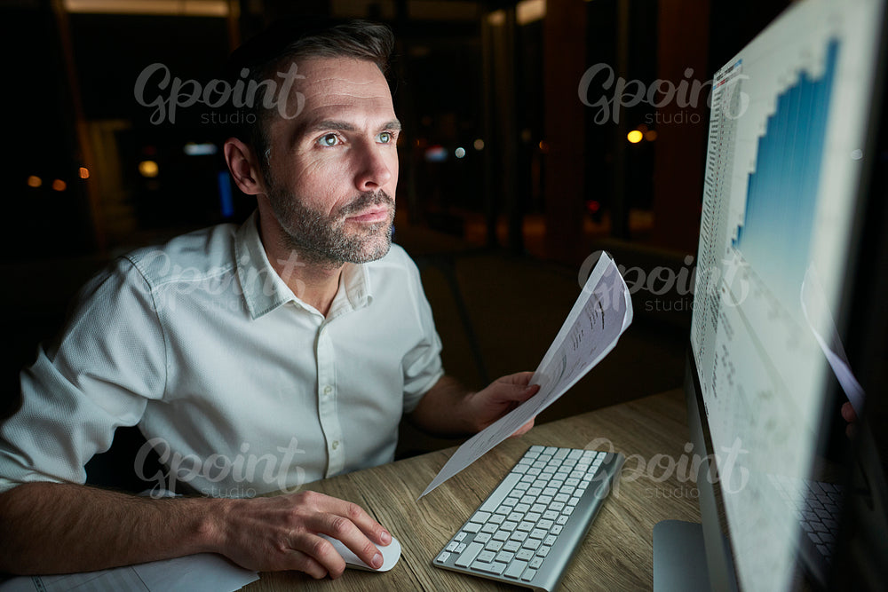 Focused man with document using computer