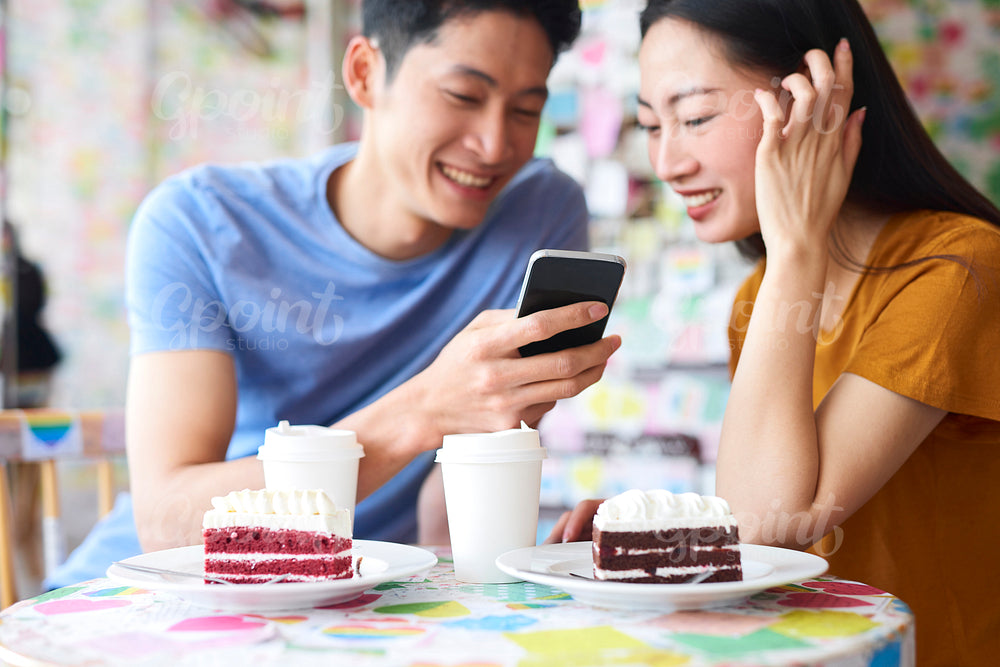 Excited couple with mobile phone in a cafe