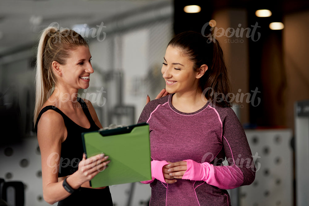 Cheerful instructor and woman at gym